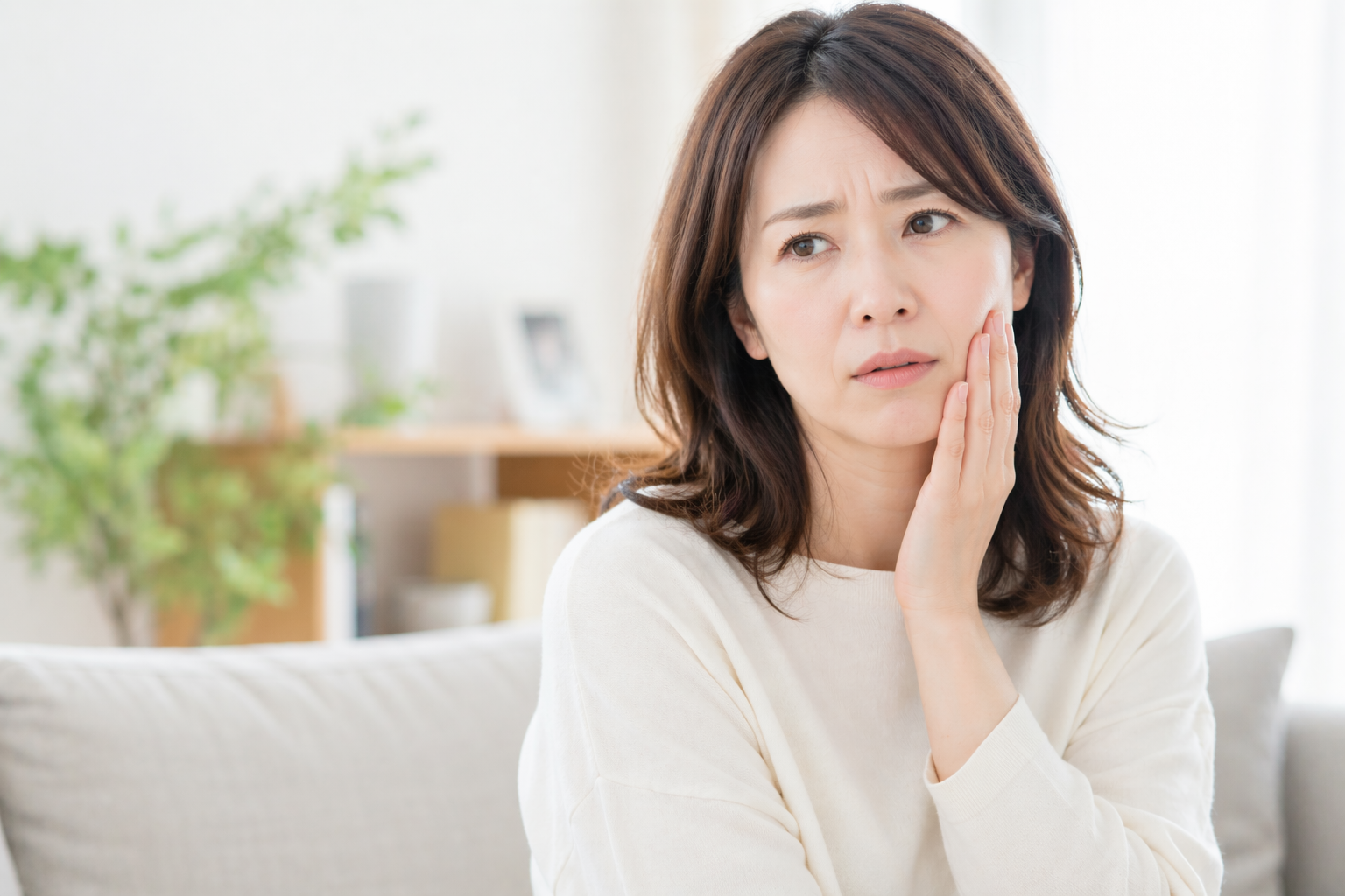 顎を押さえて悩んでいる女性